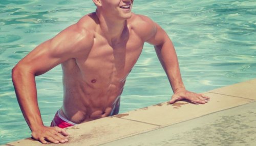 Afgetrainde man die op de zwembadrand leunt