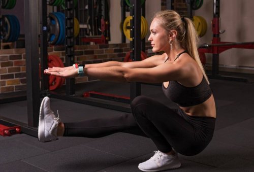 Vrouw die pistol squat doet in de sportschool