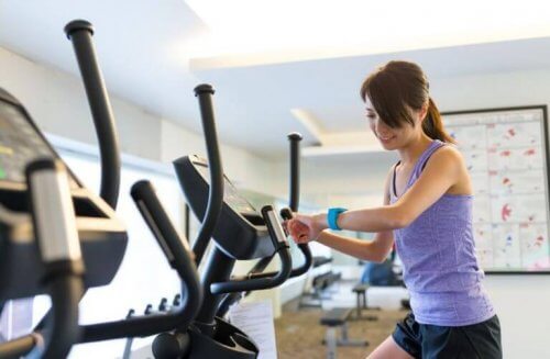 Vrouw op crosstrainer met fitness-horloge