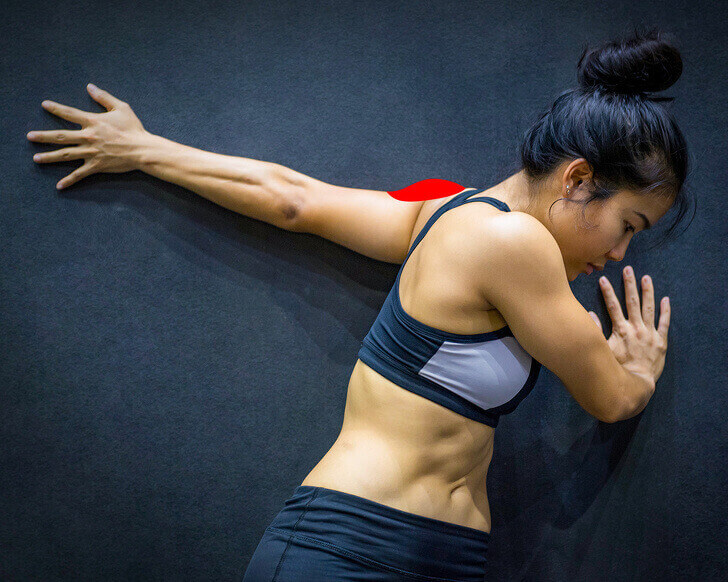 De schouders goed rekken tegen de muur aan